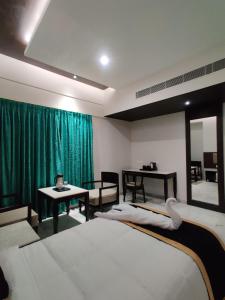 a bedroom with two beds and a green curtain at Hotel Saratharajans in Madurai