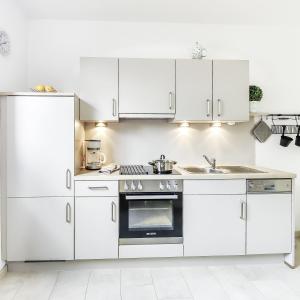 uma cozinha branca com armários brancos e um fogão em Haus Küstenperle em Cuxhaven