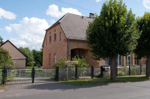 een bakstenen gebouw met een hek ervoor bij Ferienwohnung Alte Schule in Vetschau