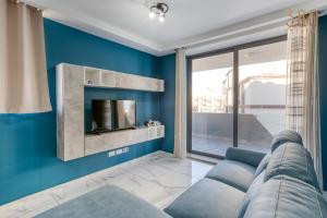uma sala de estar azul com um sofá e uma televisão em Relaxing 2BR home with Private Balcony in Mellieha by 360 Estates em Mellieħa
