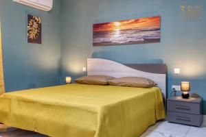 um quarto com uma cama amarela e um quadro na parede em Relaxing 2BR home with Private Balcony in Mellieha by 360 Estates em Mellieħa
