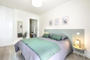 - une chambre blanche avec un grand lit et des oreillers verts dans l'établissement Résidence le Bois-Plage en Ré, au Bois-Plage-en-Ré