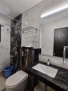 W łazience znajduje się umywalka, toaleta i lustro. w obiekcie Hotel Saratharajans w mieście Maduraj