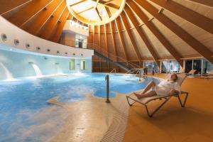 a woman sitting in a chair in front of a swimming pool at Cró Hotel Rural in Rapoula do Côa
