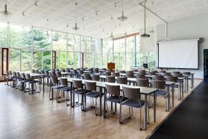 a conference room with tables and chairs and a whiteboard at Hotelli Tiiliriihi in Espoo