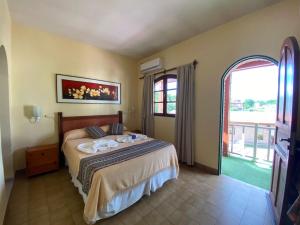 a bedroom with a bed and a large window at Hosteria de la Villa ** in Villa Cura Brochero