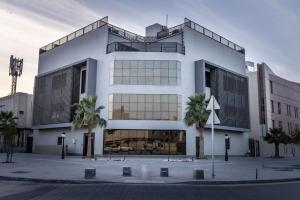 um grande edifício branco com palmeiras em frente em Nuzul R141 - Elegant Apartment em Riyadh