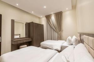 Habitación de hotel con 2 camas y espejo en Nuzul R141 - Elegant Apartment, en Riad