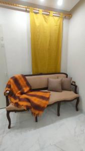 a couch with a blanket on it with a yellow curtain at Maison d'hôtes Dar Ranim Tozeur in Tozeur