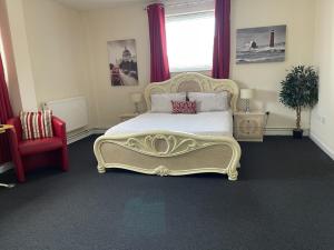 a bedroom with a large bed and a red chair at The Goodlife Guesthouse in Harwich