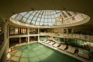 een binnenzwembad met stoelen en een glazen koepel bij Sungarden Golf & Spa Resort in Cluj-Napoca