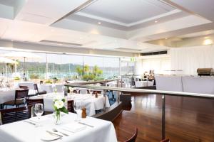 un restaurante con mesas y sillas blancas y ventanas en Metro Mirage Hotel Newport en Newport