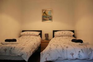 a bedroom with two beds and a picture on the wall at Terfyn Cottage in Dinorwic