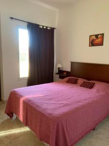 a bedroom with a pink bed with a window at Complejo Rincon del Uruguai in Colón