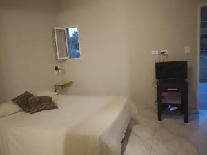 a white bedroom with a bed and a television at Nuestro Sueño in Tandil