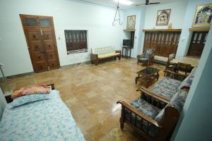 a large living room with two beds and chairs at Genga Nilayam Homestay in Virudunagar