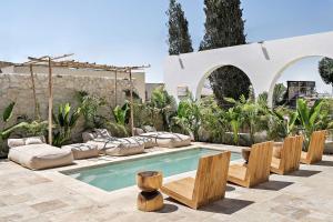 una piscina en un patio trasero con muebles y árboles en Hotel Anilevich Mansion, en Beer Sheva