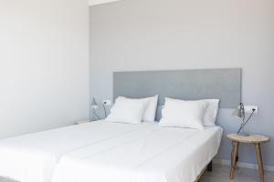 ein weißes Schlafzimmer mit einem großen Bett mit weißen Kissen in der Unterkunft Maria Paola penthouse aan het strand in Fuengirola