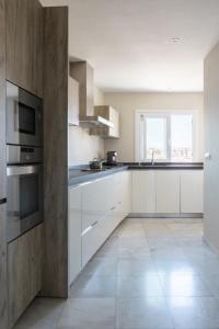 a kitchen with white cabinets and a large window at Maria Paola penthouse aan het strand in Fuengirola