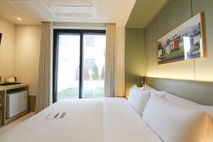 a bedroom with a white bed and a large window at Hotel Aria in Cheonan