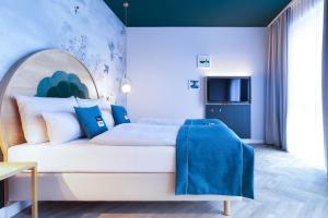 Schlafzimmer mit einem weißen Bett mit blauen Akzenten in der Unterkunft the niu Flower in Konstanz
