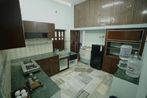 a kitchen with wooden cabinets and a counter top at Genga Nilayam Homestay in Virudunagar