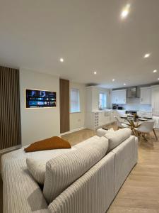 a living room with a large couch and a kitchen at Ground Floor Stratford Flat in Stratford-upon-Avon