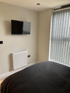 een slaapkamer met een bed en een televisie aan de muur bij 1 Bed Flat in Burton