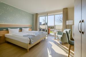 ein Hotelzimmer mit einem Bett und einem Stuhl in der Unterkunft Nordsee-Hotel Arlau-Schleuse in Husum