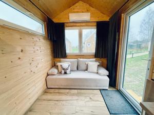 um sofá no canto de um quarto com janelas em Tiny House Village (850m od Suntago) em Grabce