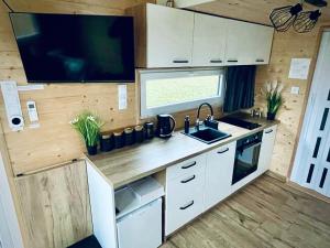 kuchnia ze zlewem i telewizor w przyczepie kempingowej w obiekcie Tiny House Village (850m od Suntago) w mieście Grabce