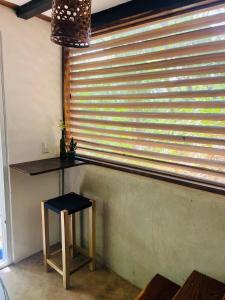 a table and a stool in front of a window at Agora at Playa Maderas - Surf House, Cabanas and Casitas in Playa Maderas