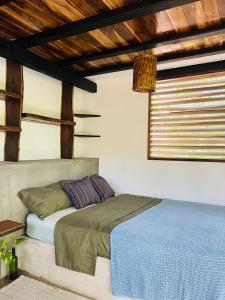 a bed sitting in a room with a window at Agora at Playa Maderas - Surf House, Cabanas and Casitas in El Plantel
