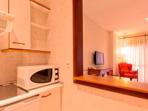 a kitchen with a microwave and a living room at Apartamentos Vértice Bib Rambla in Seville