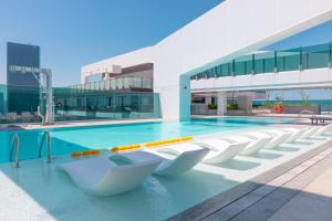 - une piscine avec des chaises blanches en face d'un bâtiment dans l'établissement Exceptional 1 BR next to Dubai Metro and World Trade Center Dubai by GP Holiday Homes, à Dubaï