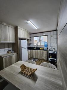 een keuken met een houten tafel en een witte koelkast bij Cobertura - Quadra Mar in Itapema