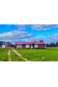 a building with a pink roof in a field at El Tambo del Anakiri in Los Muermos