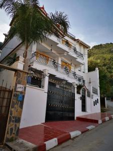 a white house with a palm tree in front of it at Niveau de Villa entre Béjaïa et Jijel (Ziama) in Jijel