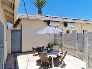 a patio with a table and chairs and an umbrella at Cosy Corner in St Helena Bay +5 photos