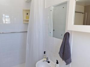 a white bathroom with a sink and a mirror at Cosy Corner in St Helena Bay