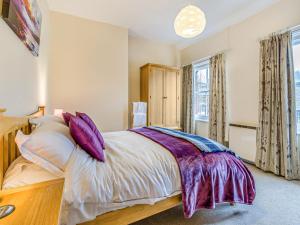 a bedroom with a large bed with purple pillows at Cobblers Flat in Llanidloes