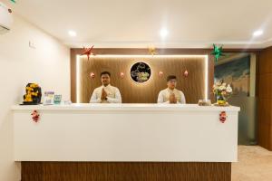 two men standing behind a counter with their ties at Hotel Dolphin International in Varanasi