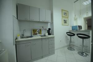 a kitchen with white cabinets and a sink and two stools at Park Lane Central Sarajevo in Sarajevo