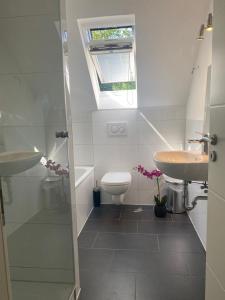 ein Bad mit einem Waschbecken, einem WC und einem Fenster in der Unterkunft ND Hotels & Apartment Superior Bottrop in Bottrop