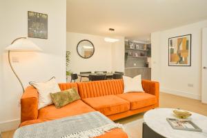 an orange couch in a living room with a table at Be London - The Marylebone Residences in London