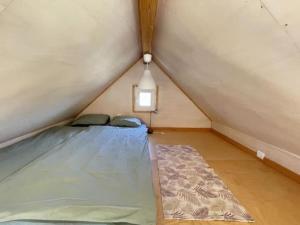 a room with a bed and a rug in a attic at Da Silva Surfcamp, Tiny House Luna in Lourinhã