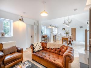 a living room with a brown leather couch and a kitchen at The Ostlers Cottage in Sleaford