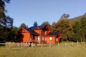 a wooden house in the middle of a field at Cabañas Los Canelos Hermosa granja en Pucón in Pucón