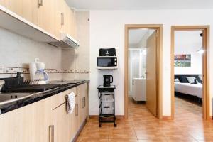 a kitchen with a sink and a microwave and a bedroom at Casa Lolina in Maspalomas