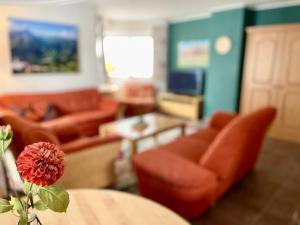 ein Wohnzimmer mit einem Sofa und einem Tisch mit einer Blume in der Unterkunft Ferienwohnung Garten Eden Sommer-Hörnerbahnen kostenlos in Bolsterlang